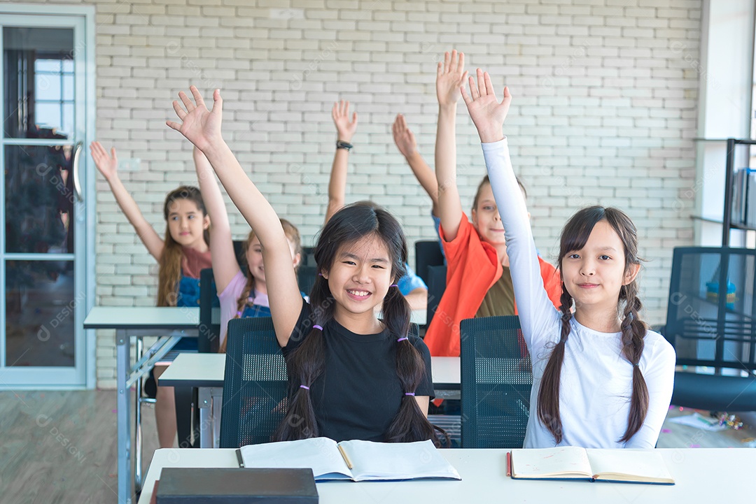 Estudantes de escolas internacionais levantam as mãos juntas na aula