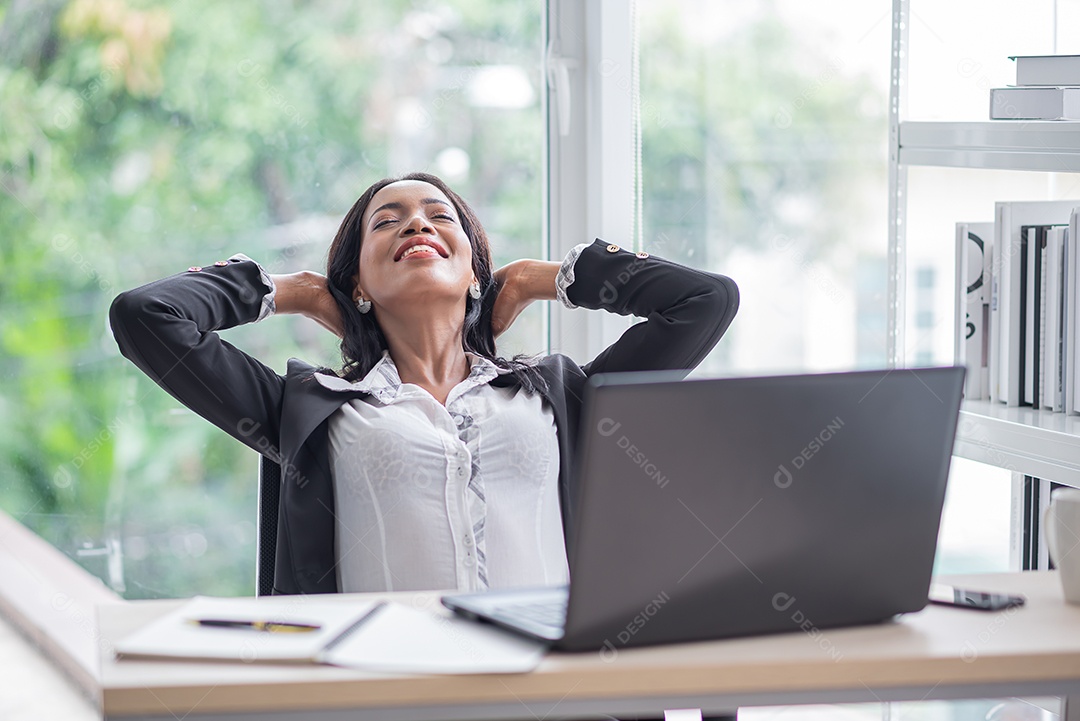 Mulher de negócios africana faz pose relaxante na mesa enquanto senta e trabalha
