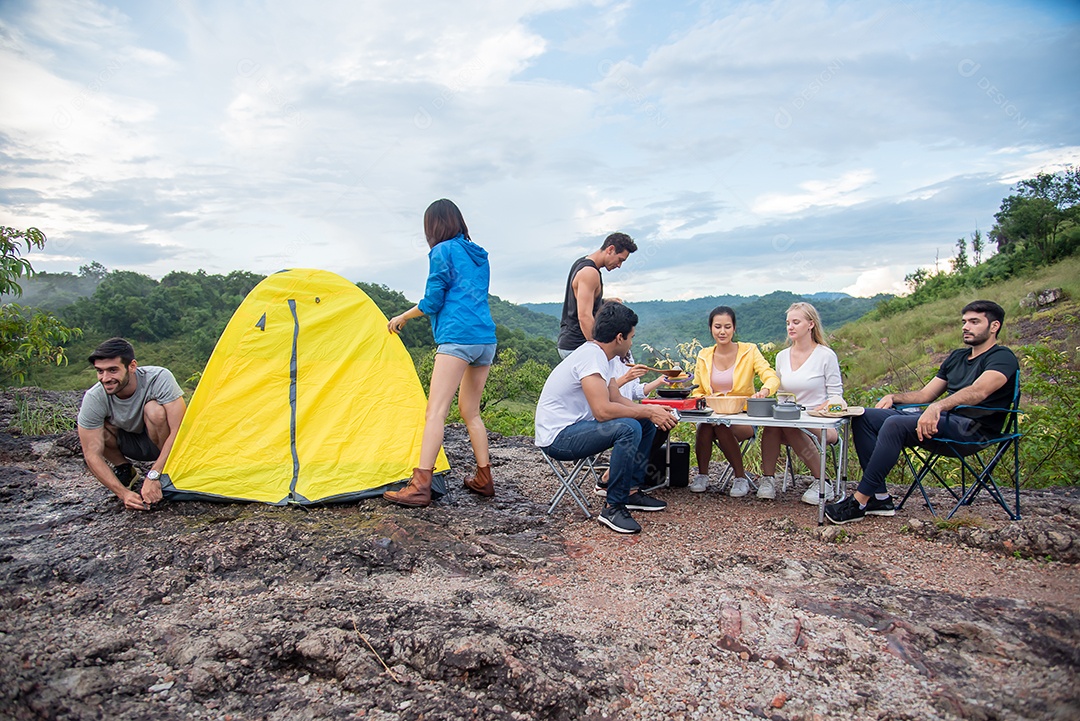 Grupo de amigos homens e mulheres preparam uma mesa de piquenique