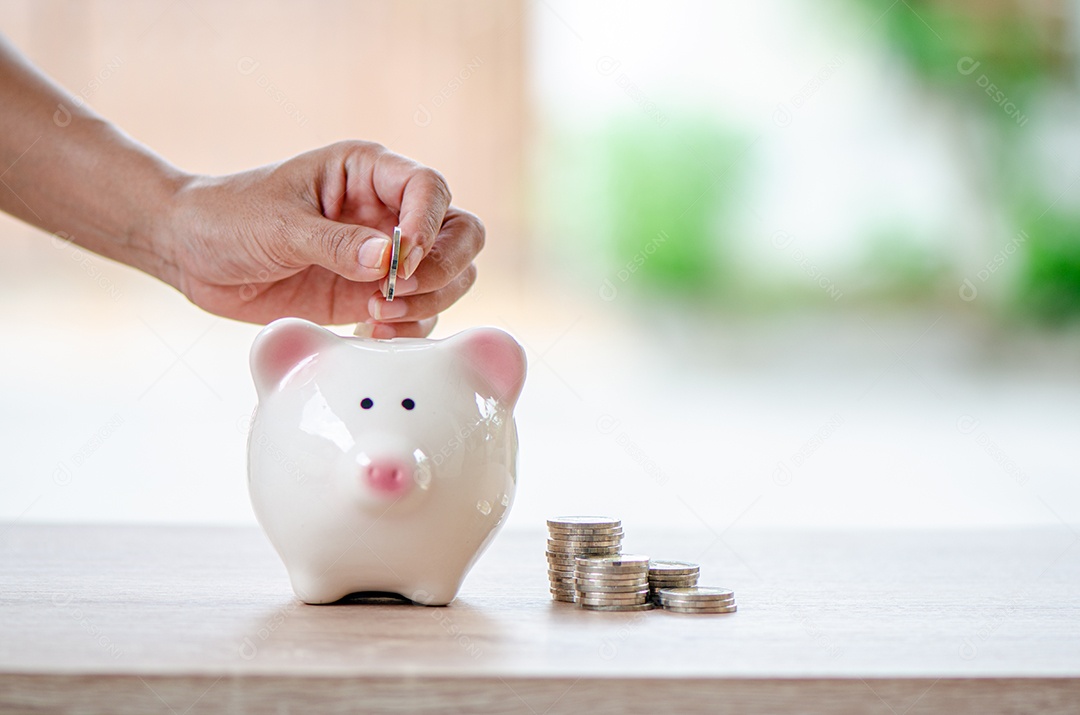 Mão de homem joga moeda no cofrinho