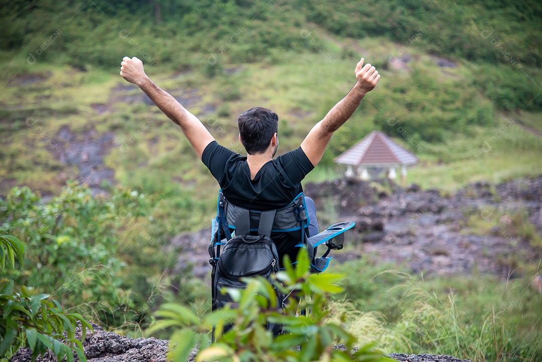 Homem se senta em uma cadeira relaxando entre as belas montanhas