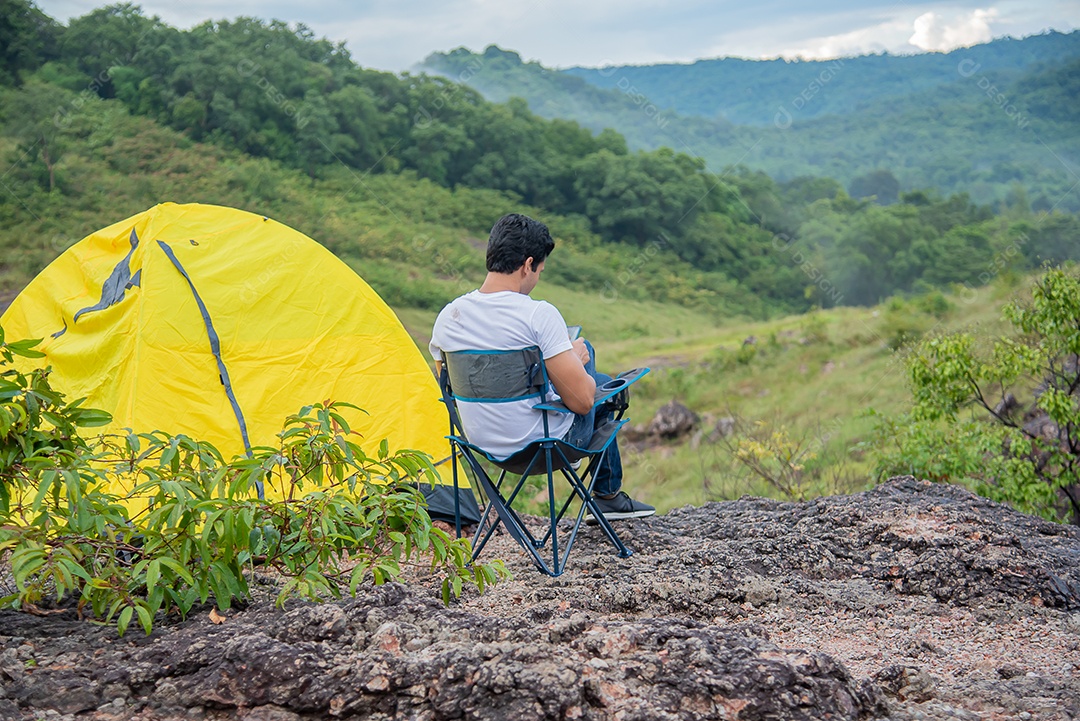 Homem se senta em uma cadeira relaxando entre as belas montanhas