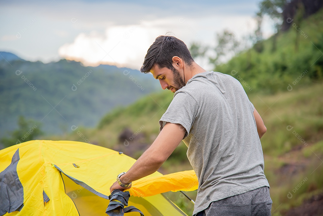 Jovem está armando tendas entre as belas montanhas