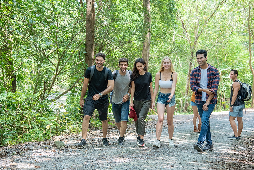 Amigos estão caminhando em bosques ensolarados de primavera, conversando e rindo