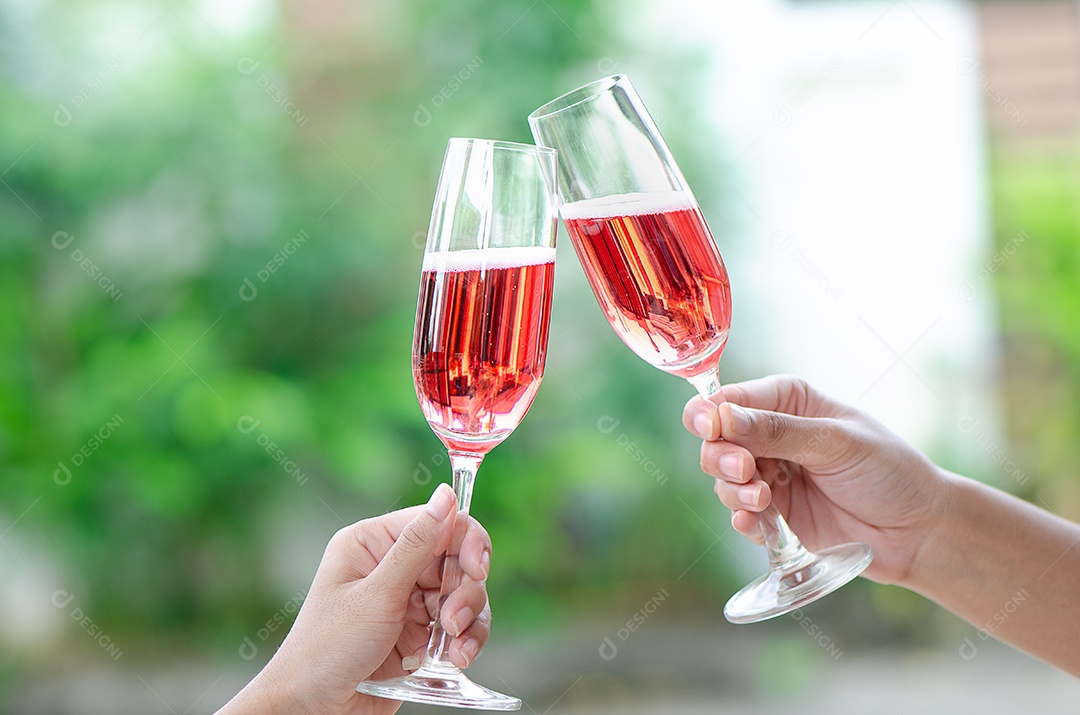 Duas pessoas segurando duas taças de vinho tinto em um jantar de comemoração