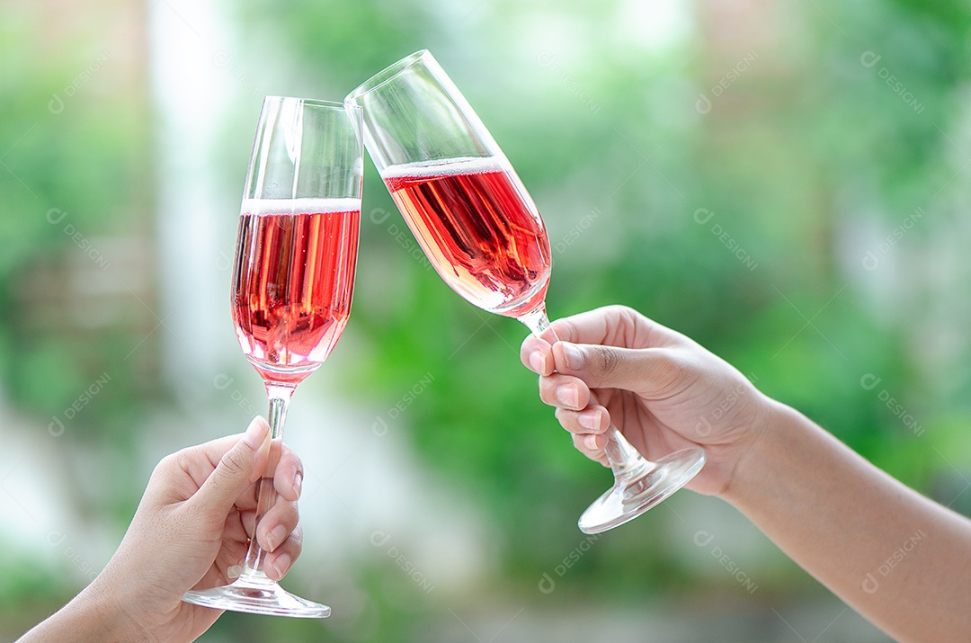 Duas pessoas segurando duas taças de vinho tinto em um jantar de comemoração