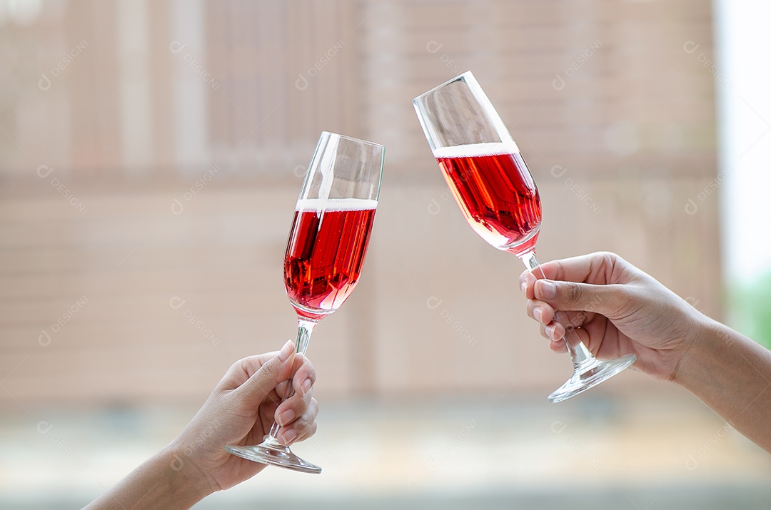 Duas pessoas segurando duas taças de vinho tinto em um jantar de comemoração