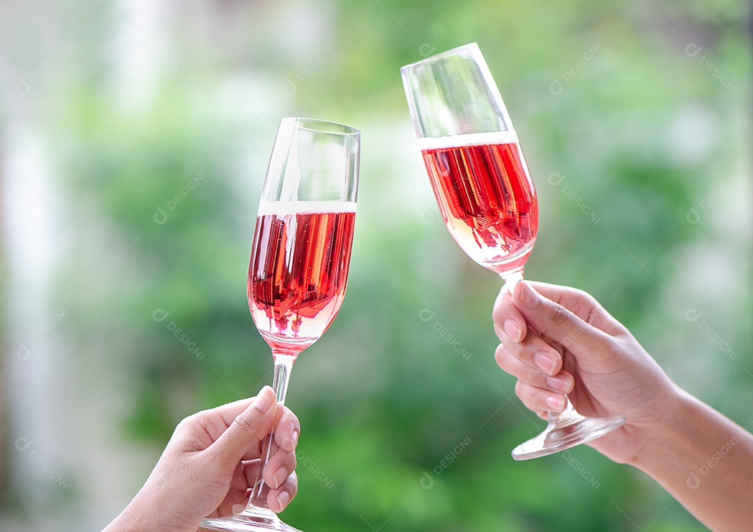 Duas pessoas segurando duas taças de vinho tinto em um jantar de comemoração