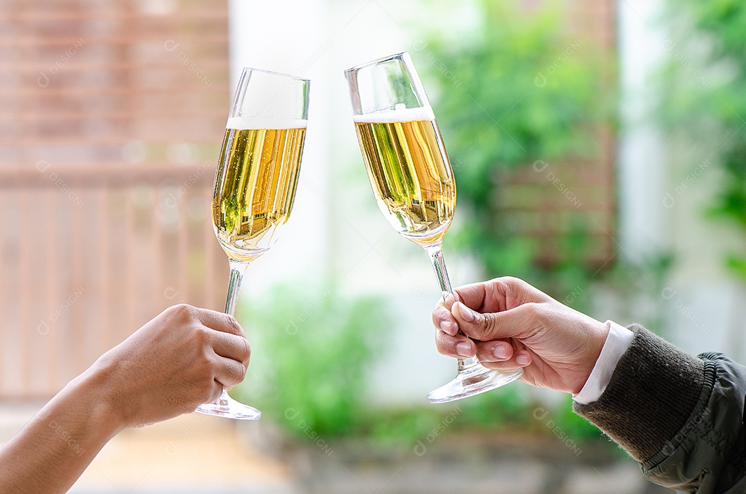 Duas pessoas segurando duas taças de vinho tinto em um jantar de comemoração