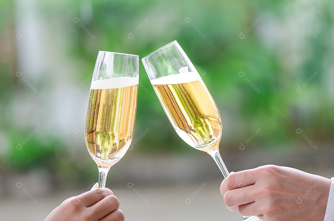 Duas pessoas segurando duas taças de vinho tinto em um jantar de comemoração