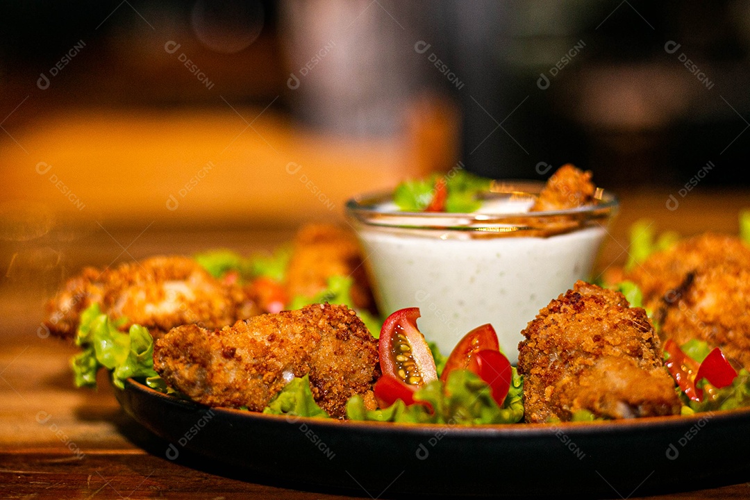 Frango a passarinho servido em bandeja com salada de alface e tomate