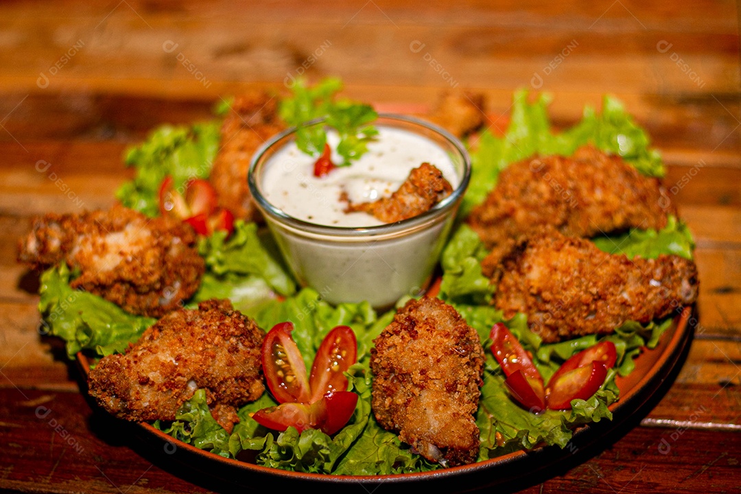 Frango a passarinho servido em bandeja com salada de alface e tomate