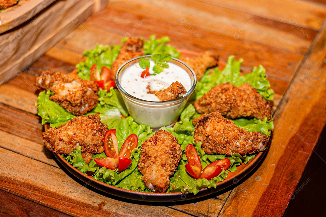 Frango a passarinho servido em bandeja com salada de alface e tomate