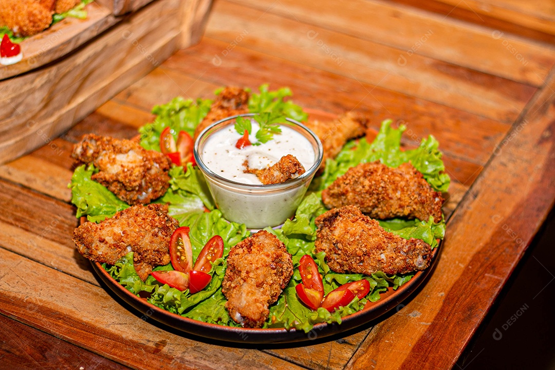 Frango a passarinho servido em bandeja com salada de alface e tomate