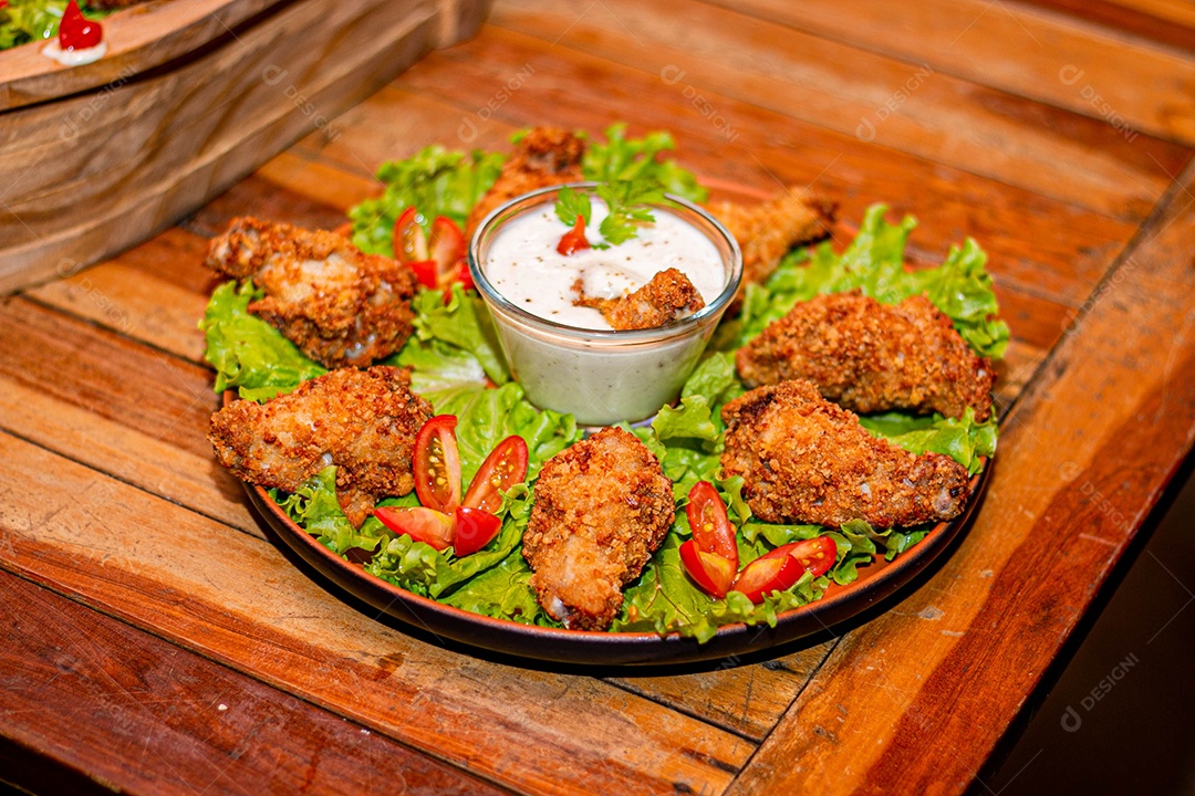 Frango a passarinho servido em bandeja com salada de alface e tomate