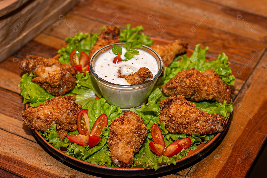 Frango a passarinho servido em bandeja com salada de alface e tomate