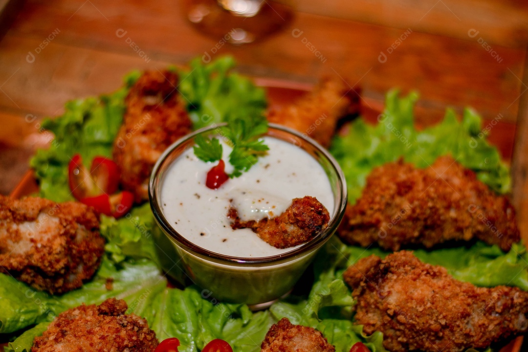 Frango a passarinho servido em bandeja com salada de alface e tomate