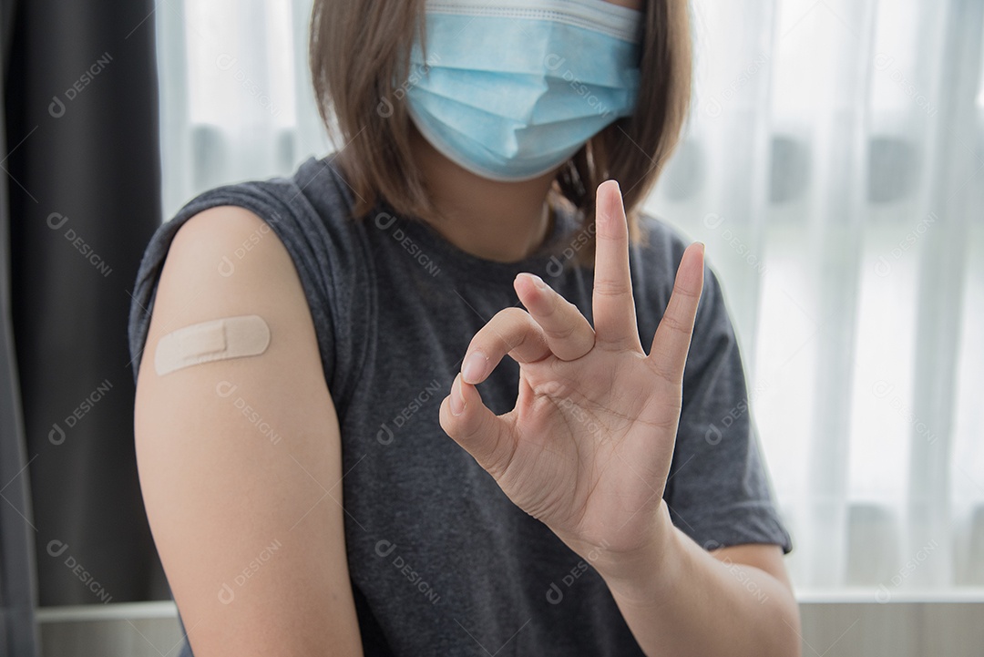 Linda mulher asiática mostra símbolo ok depois de ser vacinada