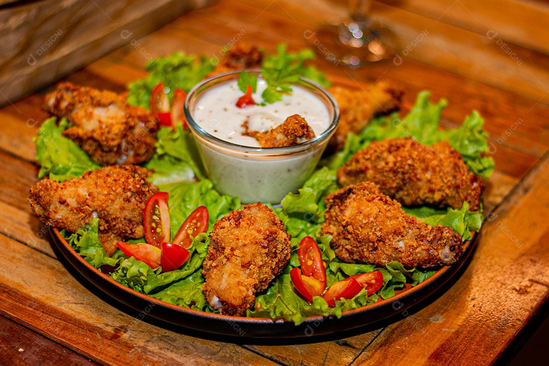 Frango a passarinho servido em bandeja com salada de alface e tomate