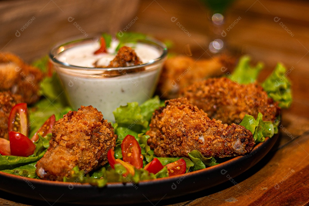 Frango a passarinho servido em bandeja com salada de alface e tomate