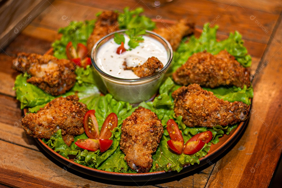 Frango a passarinho servido em bandeja com salada de alface e tomate