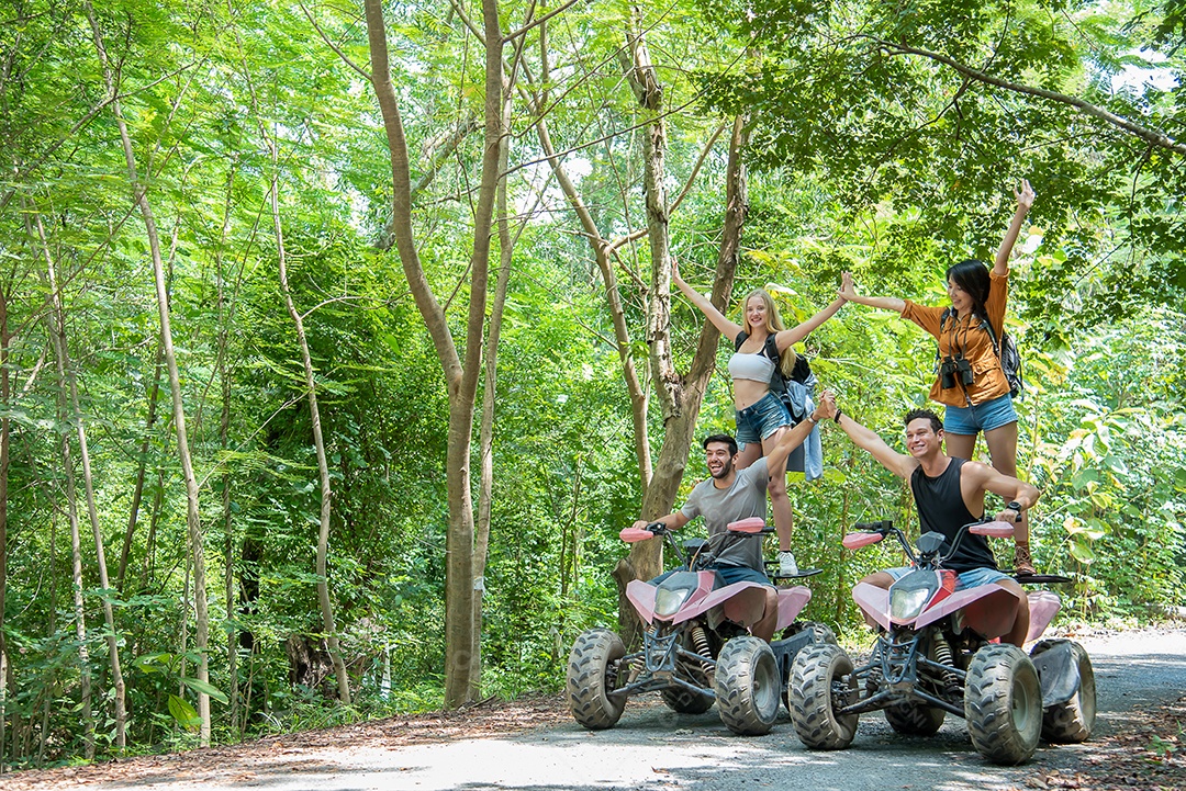 Jovem casal ou amigo alegremente toca suas mãos enquanto monta em um quadriciclo na floresta.