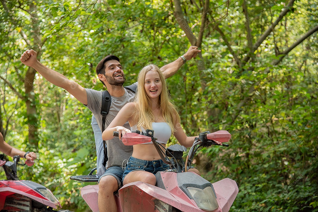 Jovem casal ou amigo feliz enquanto andava de quadriciclo na floresta