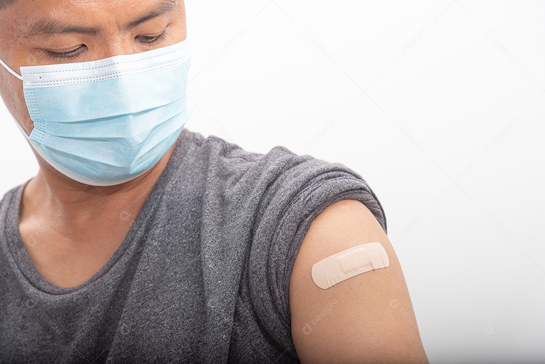 Homem asiático usa máscara e olha o braço depois de ser vacinado