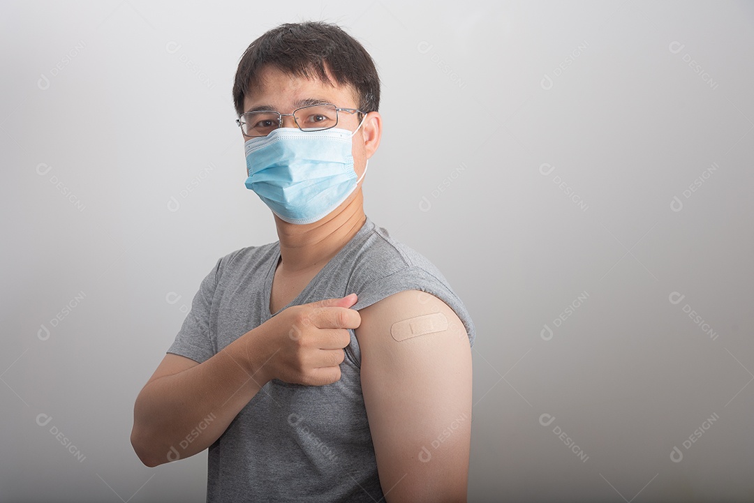 Homem asiático usa máscara mostrando braço recebendo vacinação COVID