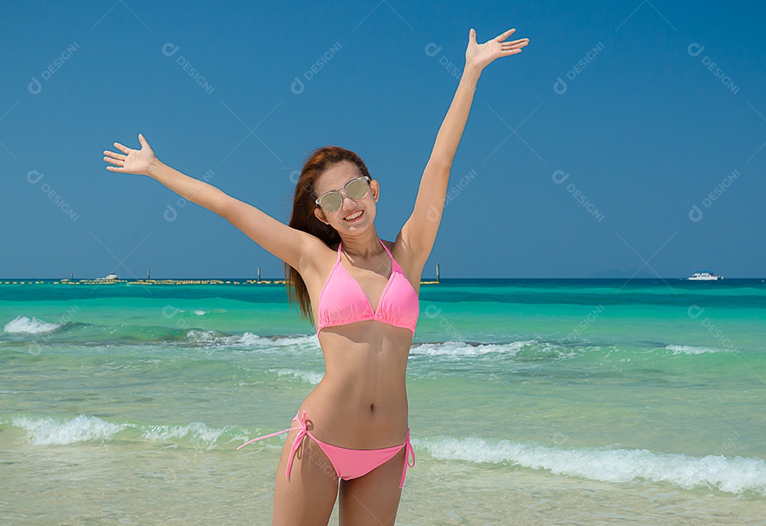 Linda mulher asiática veste alegremente um biquíni rosa e veste cantada