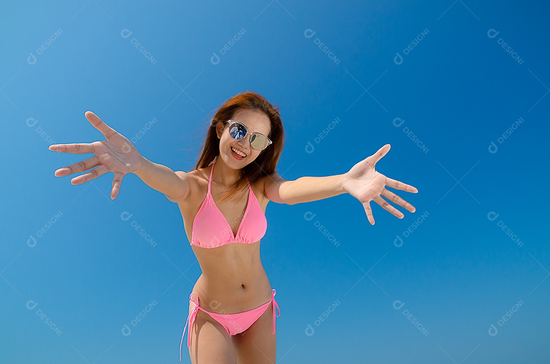 Linda mulher asiática veste alegremente um biquíni rosa e veste cantada