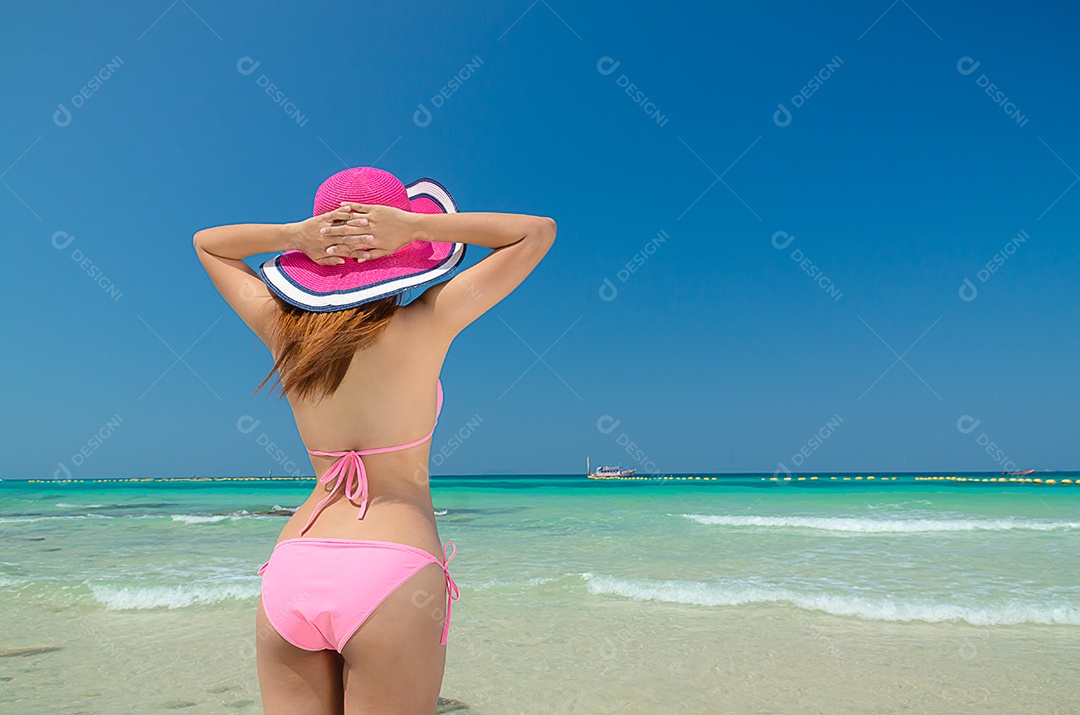 Linda mulher asiática veste alegremente um biquíni rosa e veste cantada