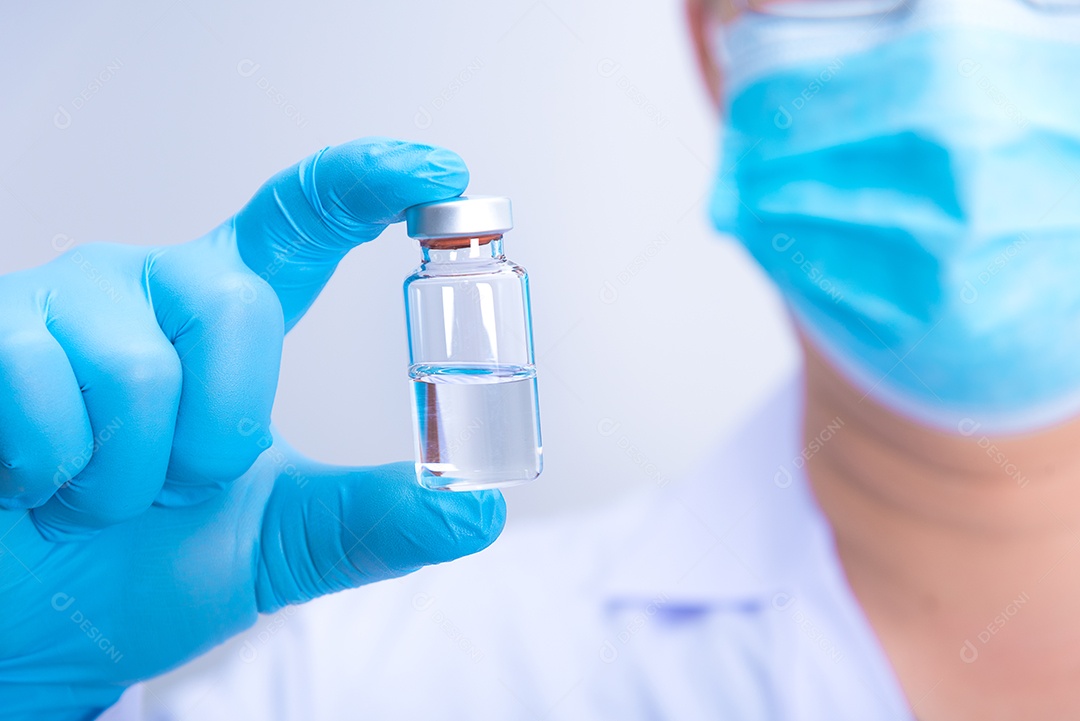O médico usando luvas e máscara azuis está segurando a vacina contra o vírus