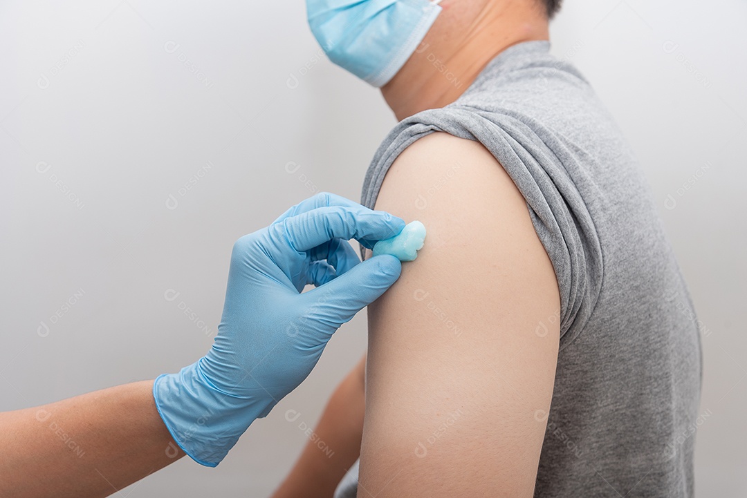 Enfermeira limpe o braço com álcool antes de aplicar a injeção