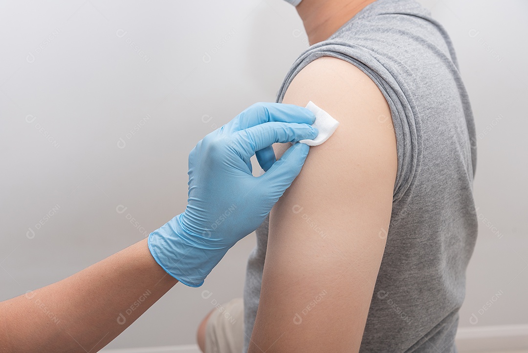 Enfermeira limpe o braço com álcool antes de aplicar a injeção