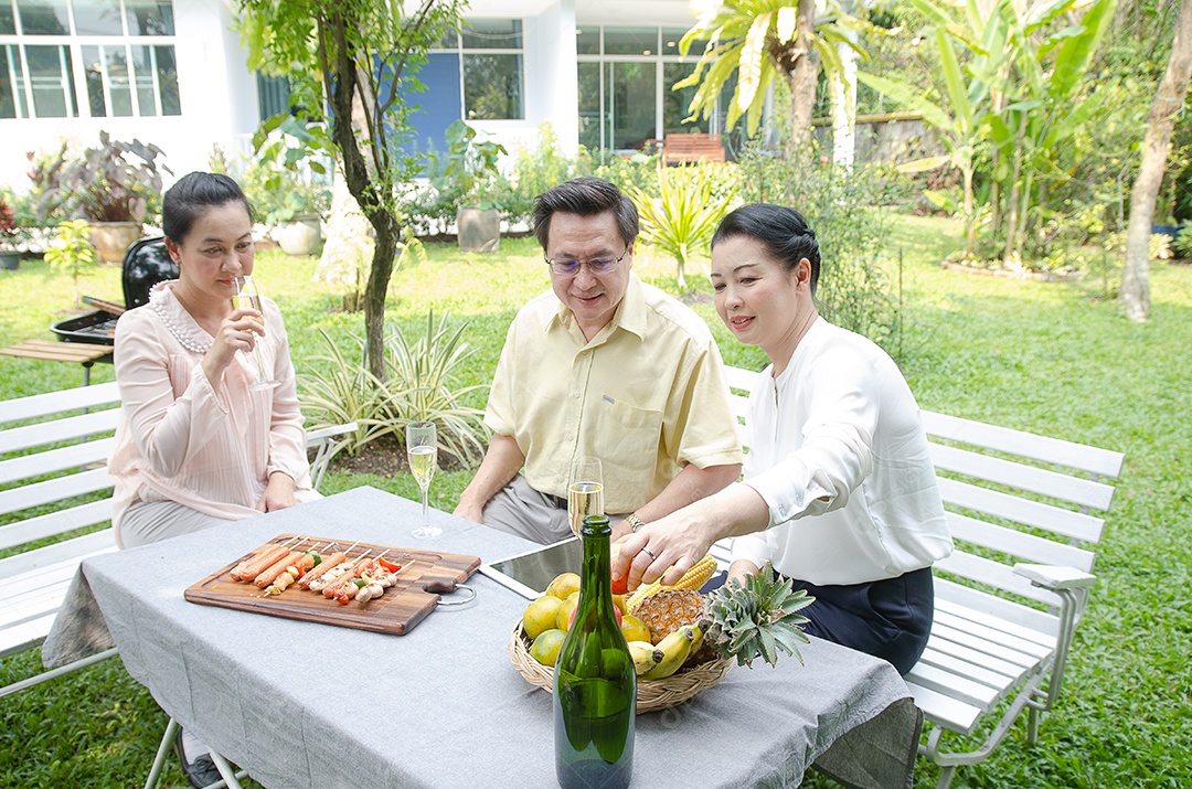 Grupo de idosos comemorando com vinho branco e churrasco