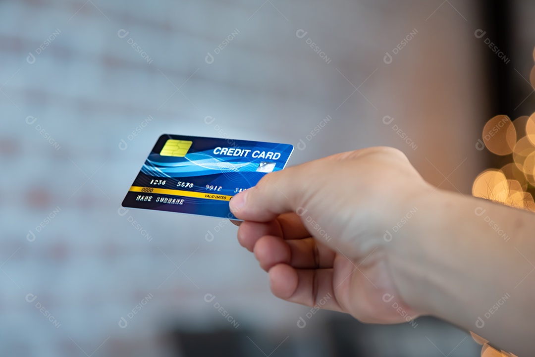 Mão segure o fundo azul do bokeh dos cartões de crédito