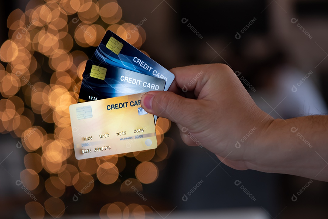 O homem segura o fundo do bokeh dos cartões de crédito da árvore