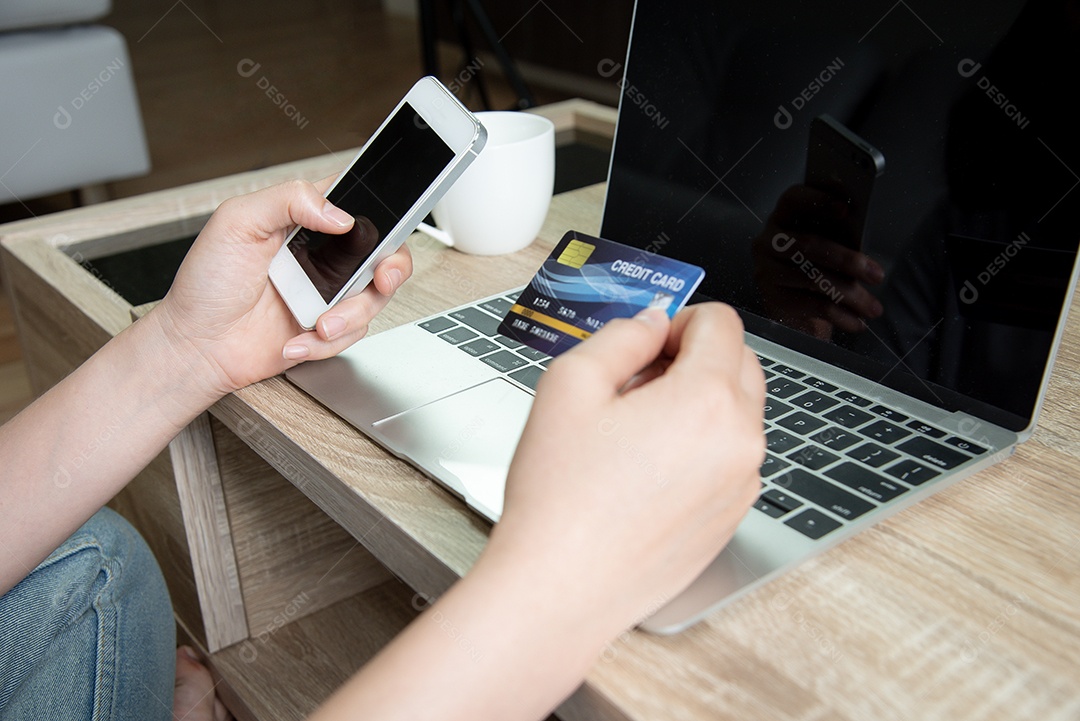 Mulher usa telefones celulares e cartões de crédito para fazer compras online