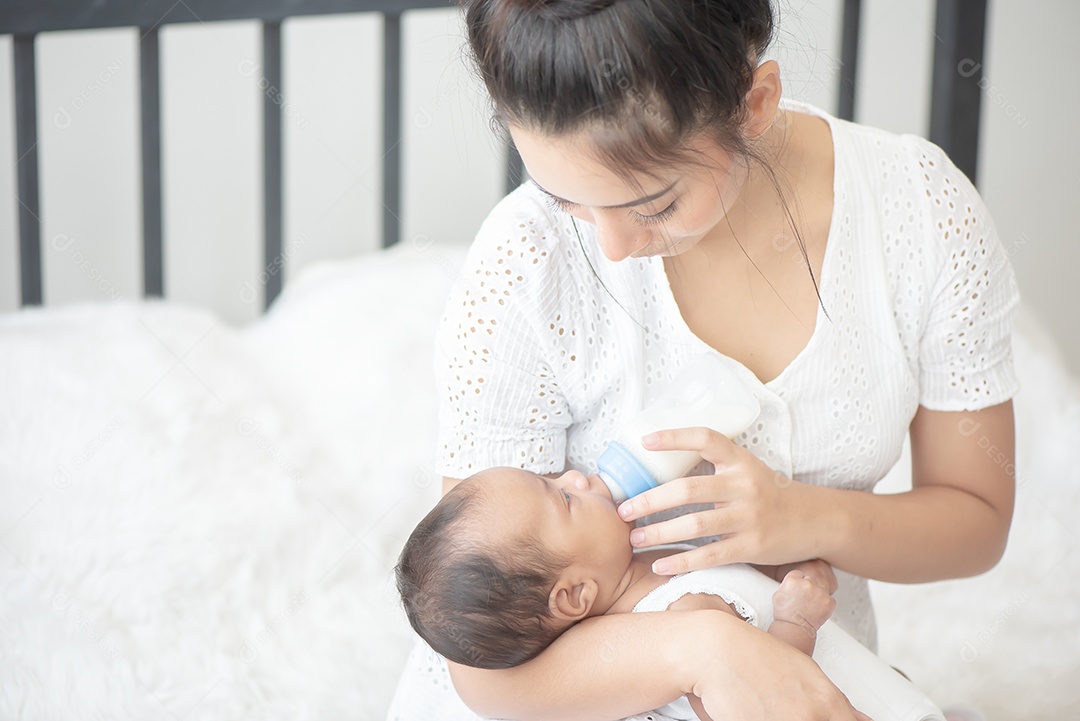 Linda mãe asiática está feliz enquanto alimenta o bebê