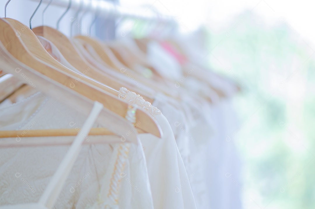 Muitos vestidos de noiva penduram no varal no casamento de estúdio