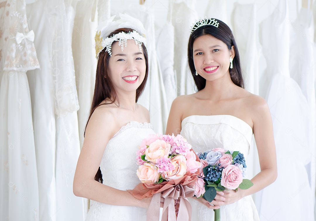 Duas noivas asiáticas sorriem alegremente e carregam flores no casamento