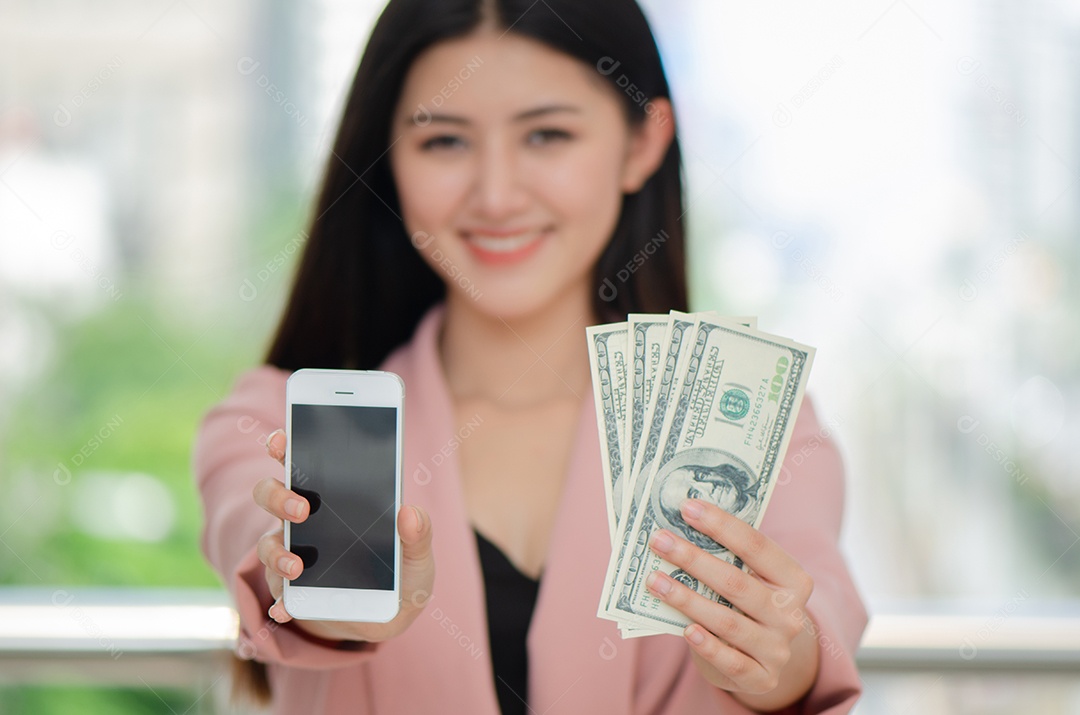 Bela jovem asiática segura dinheiro, sorriso móvel e felicidade
