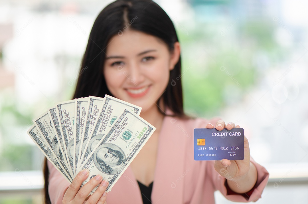 Bela jovem asiática segurando dinheiro e cartão de crédito