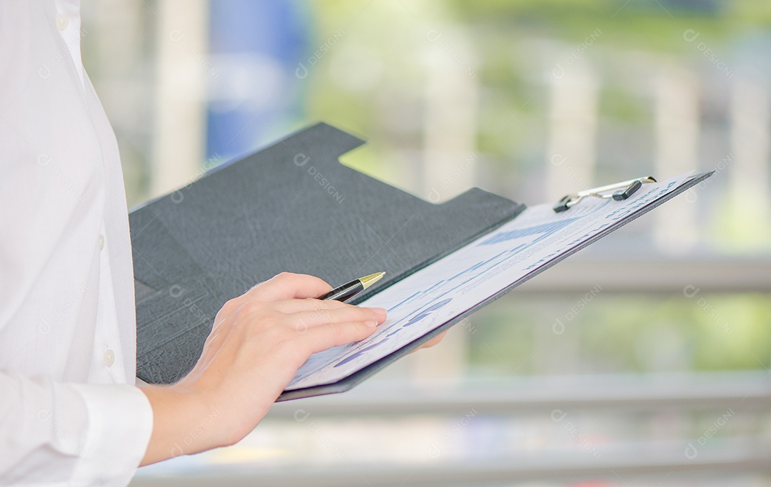 Mulher de negócios segurando caneta e verificando relatórios financeiros