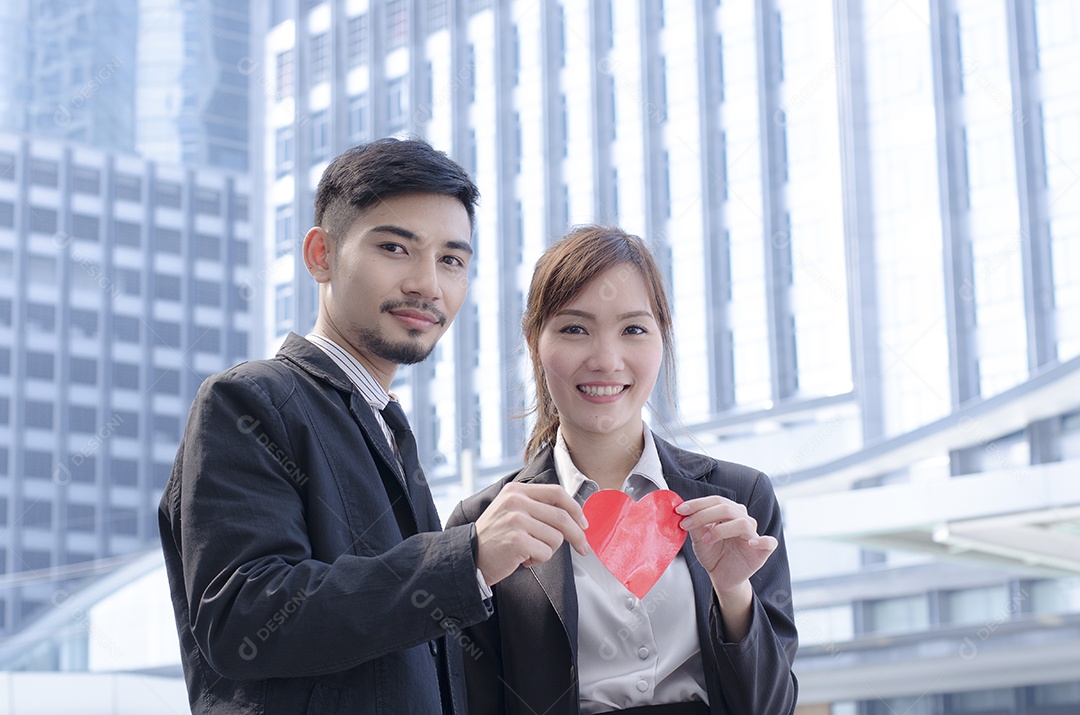 Mulher jovem e bonita segurando o coração. Ambos se sentem felizes e sorridentes.
