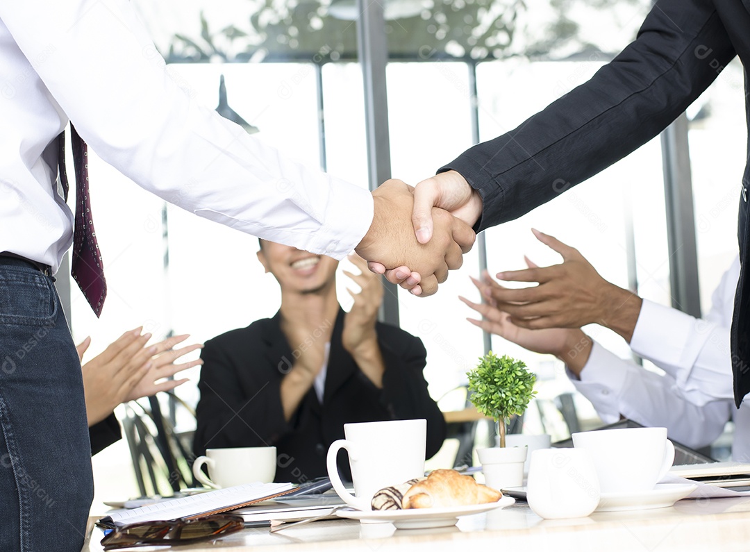 Empresários apertam as mãos com aplausos e sorrisos.