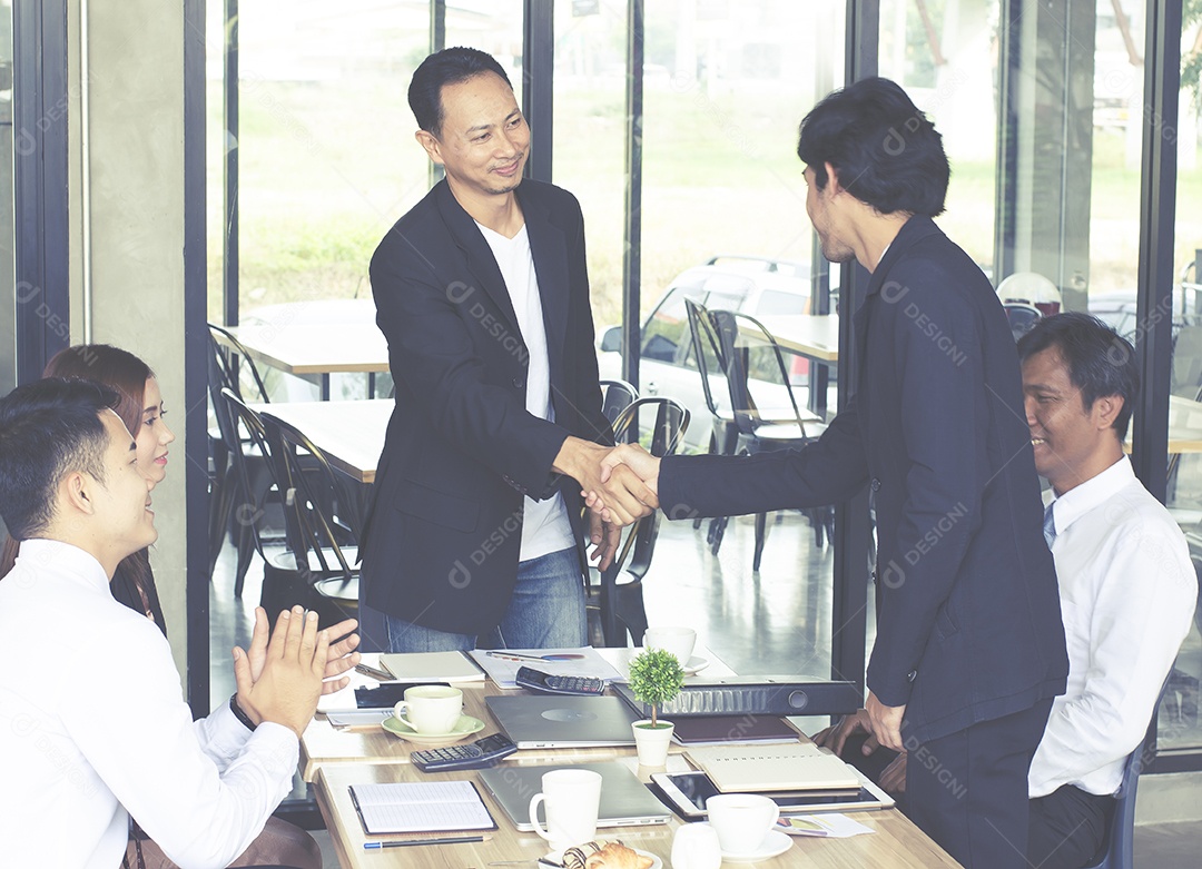Empresários apertam as mãos com aplausos e sorrisos.