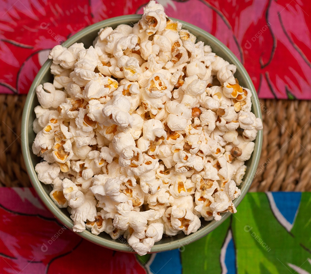 Tigela grande cheia de pipoca na mesa de palha