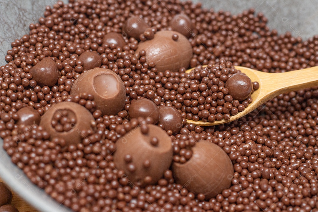Bolas de chocolate em uma tigela cinza com uma colher cheia de chocolate
